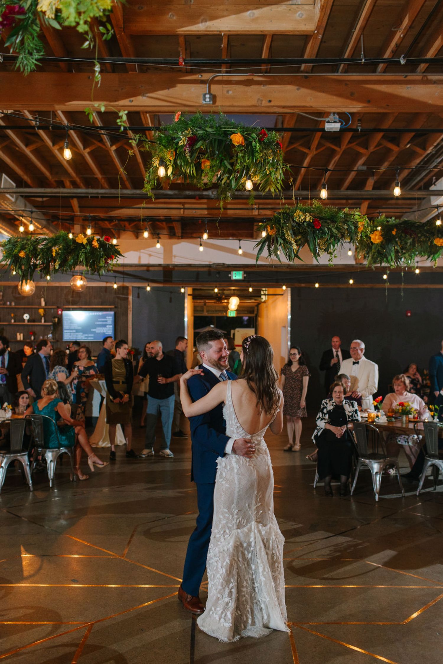 Bride and groom's first dance with greenery chandeliers