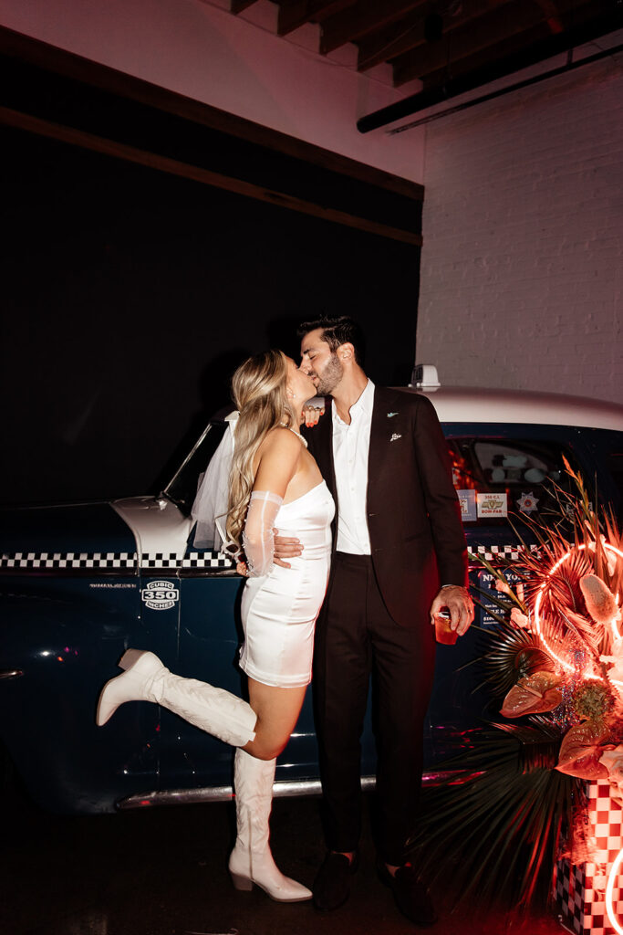 Wedding photos with vintage taxi cab at SKYLIGHT groom kissing bride