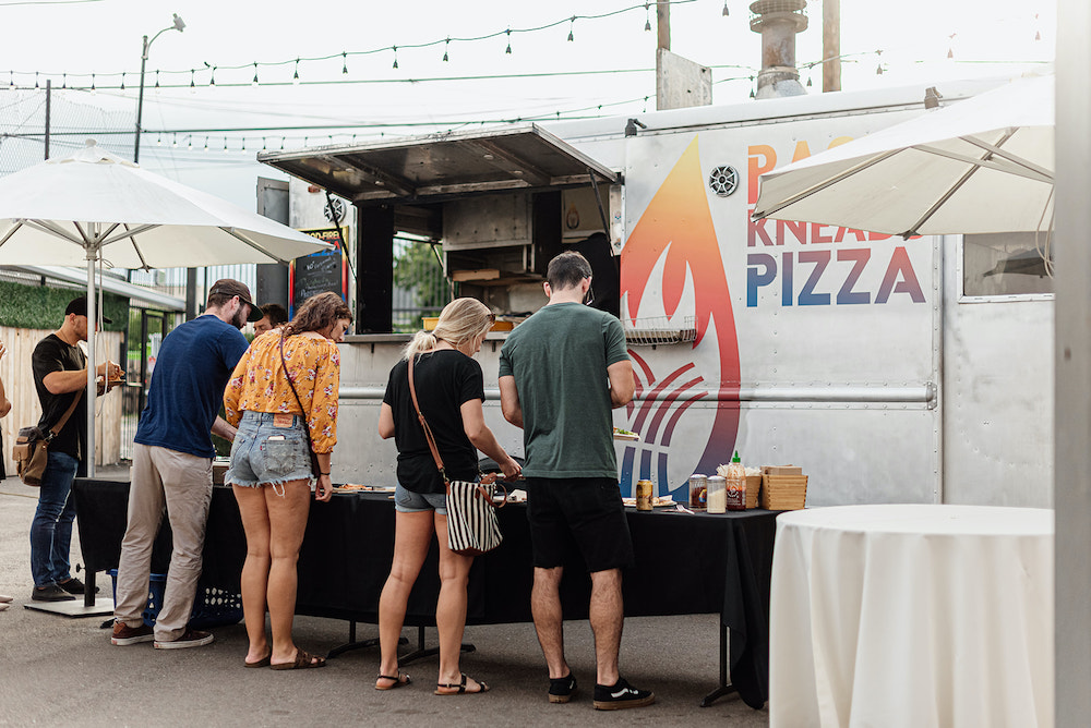 Guests at a corporate event getting pizza from a food truck at SKYLIGHT in Denver