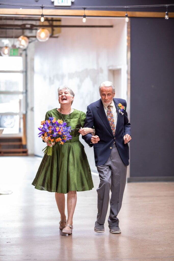 Bride in green dress is walked down the aisle