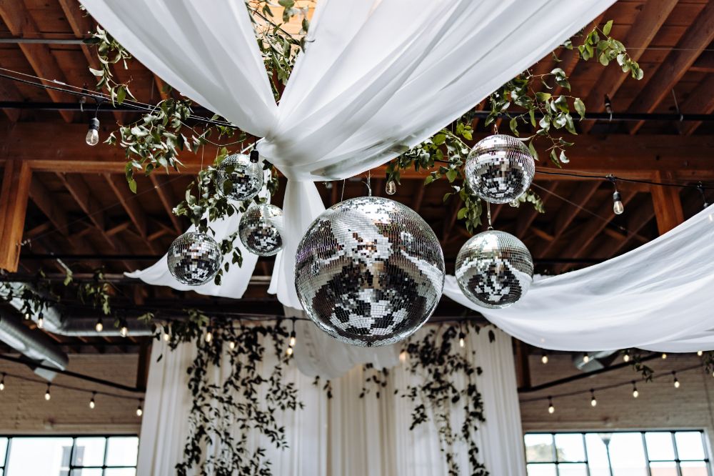 Disco balls, draping and greenery hanging from SKYLIGHT's rafters