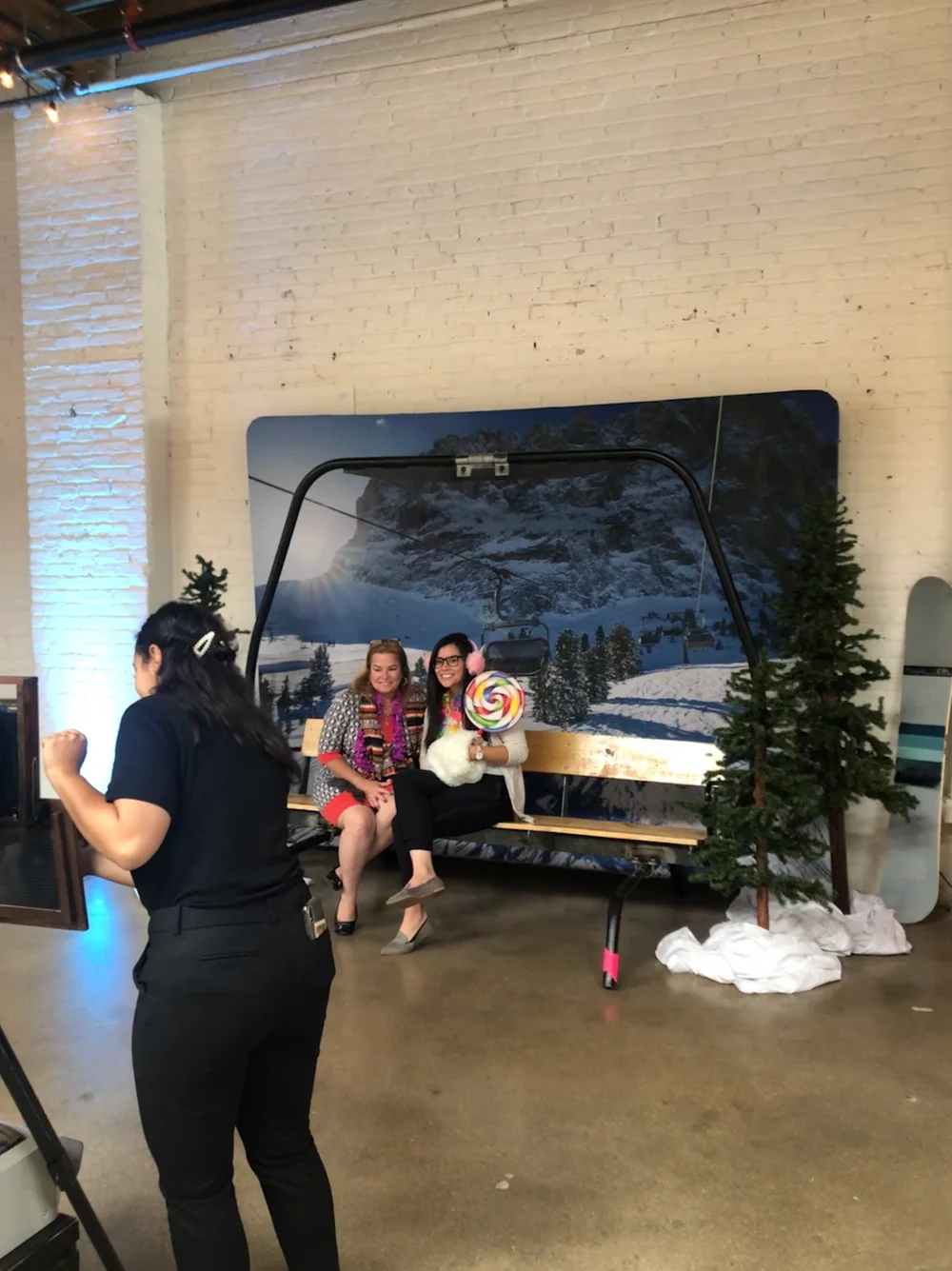 Women posing in front of a painted winter backdrop for a photo at company holiday party in Denver.