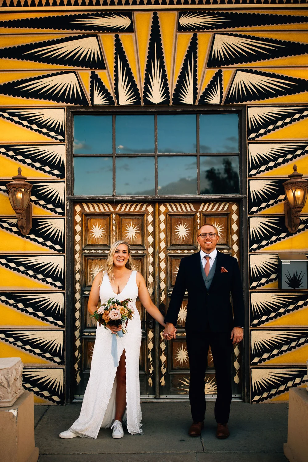 Bride and groom in front of a vibrant yellow mural in the Santa Fe Arts District of Denver