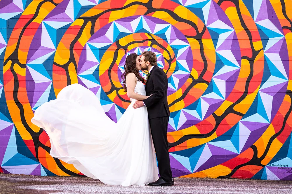 Bride and groom kissing in front of a colorful mural in the Santa Fe Arts district of Denver