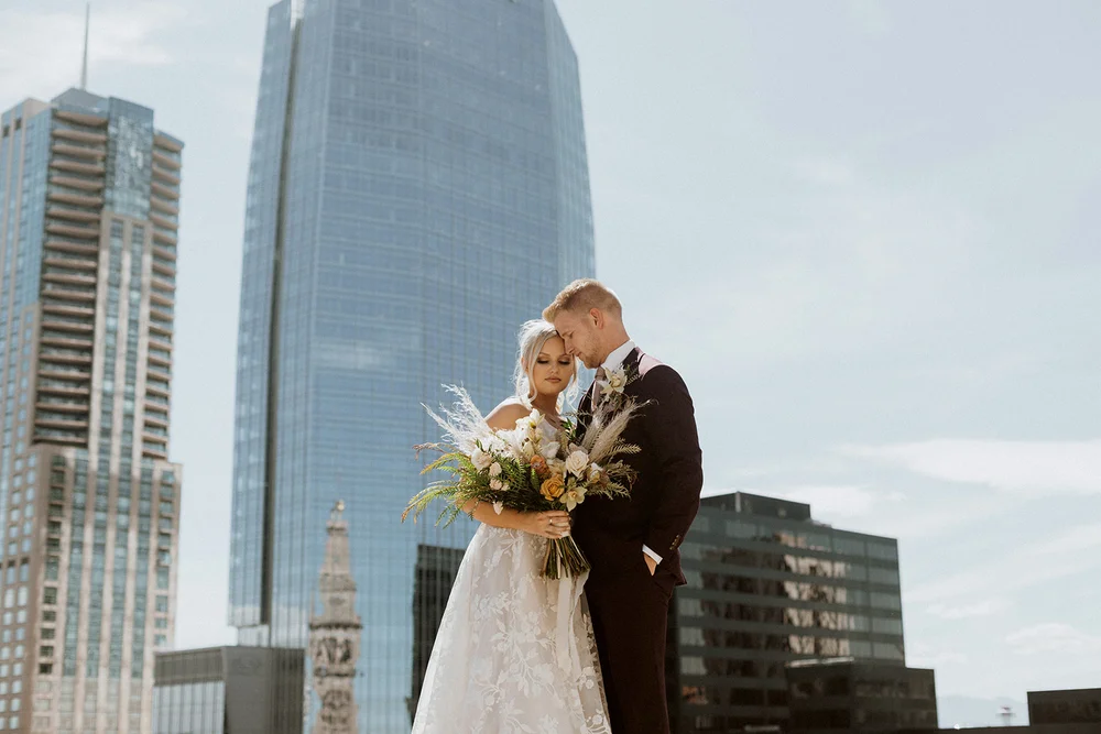 Bride and groom standing on a rooftop with views of the Denver skyline for wedding photos