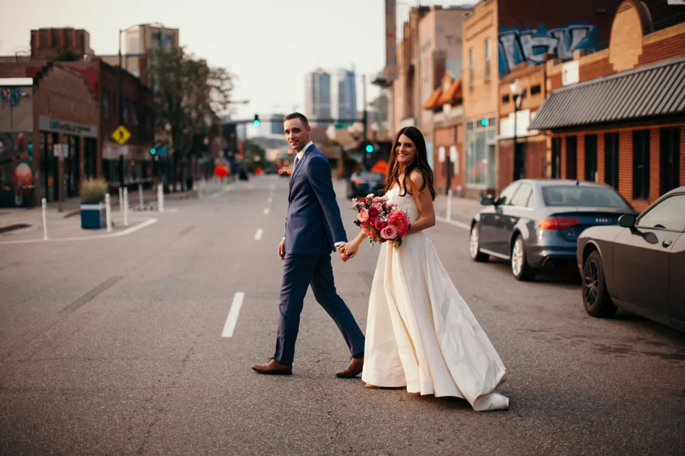 Bride and groom walking down a street in Denver’s Santa Fe Arts District for wedding photos