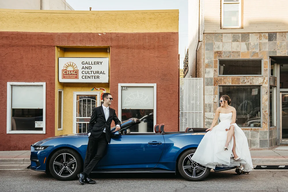 Bride and groom sitting on a convertible on Santa Fe Drive in Denver, Colorado for wedding photos