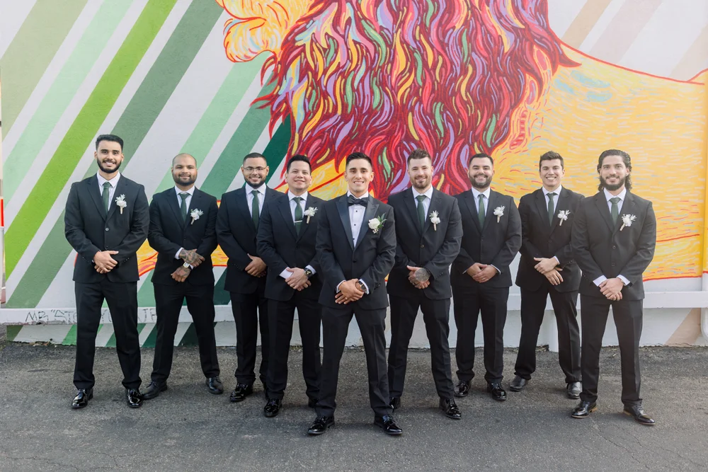 Groom and groomsmen posing in front of a colorful mural in Denver’s Santa Fe Arts District for wedding photos