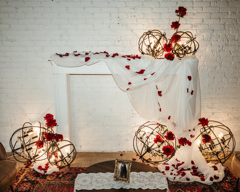 Lounge area with faux fireplace, white draping, and red roses at SKYLIGHT Denver wedding venue open house