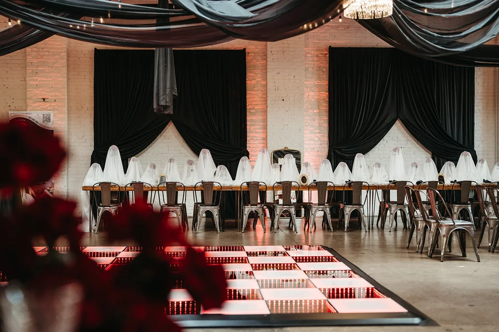Open house setup at SKYLIGHT Denver wedding venue with checkered dance floor, dark draping, and red rose tablescape