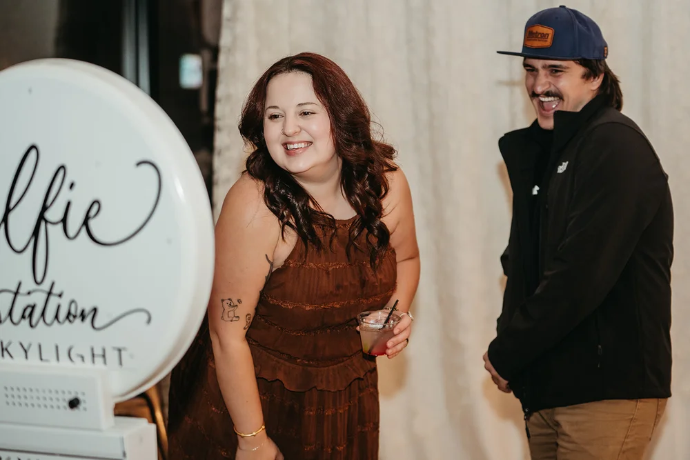 Woman and man posing in front of SKYLIGHT Denver wedding venue photo booth