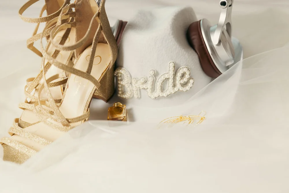 Wedding day details featuring a white hat with “Bride” beaded lettering, styled for a Denver wedding
