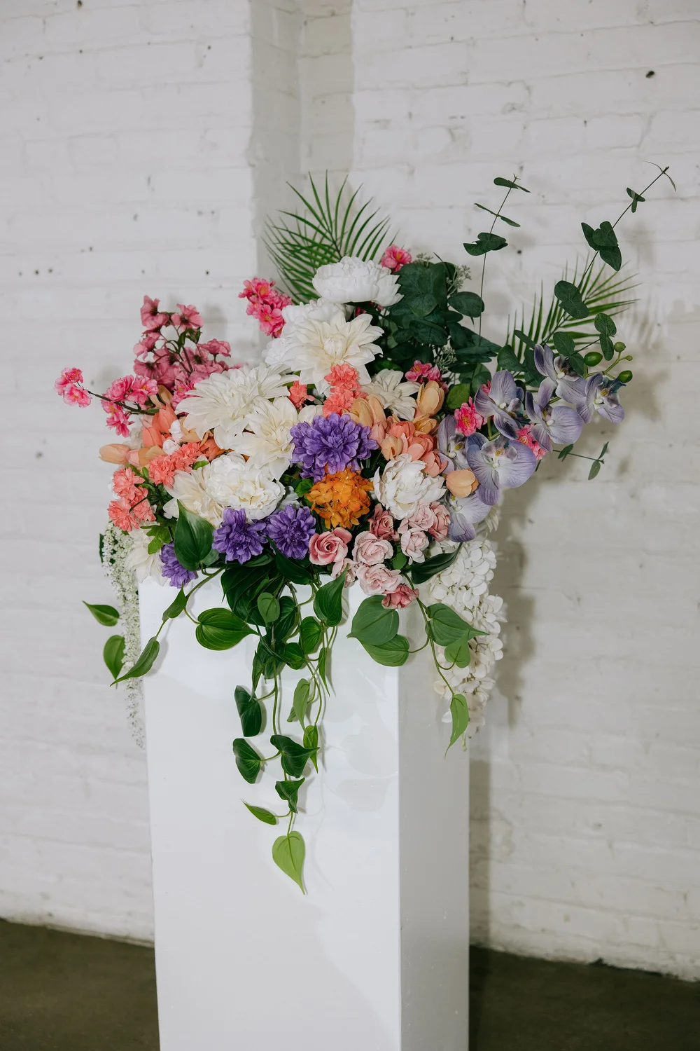 Wedding florals arranged on a white pillar at SKYLIGHT, a Denver wedding venue