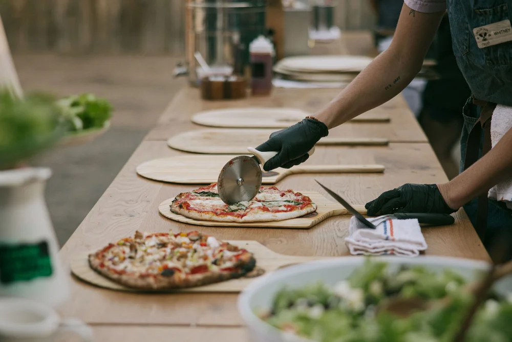 Chef slicing a freshly prepared pizza, a detail from a Denver wedding catering setup