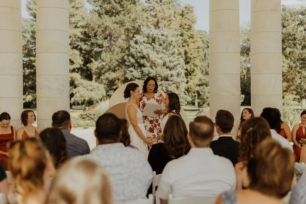 Brides saying their vows at an outdoor summer wedding ceremony at Cheesman Park in Denver CO