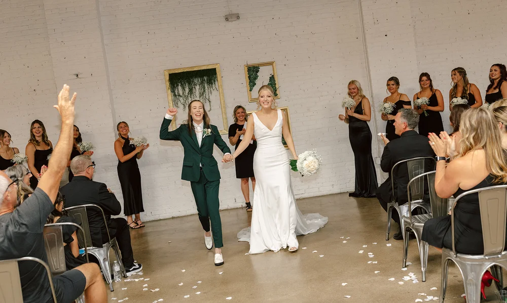 LGBTQ+ brides walking down the aisle after their wedding ceremony at SKYLIGHT in Denver CO